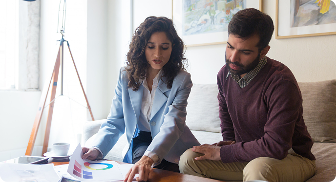 Two people reviewing colorful charts and notes at a table in a bright office.