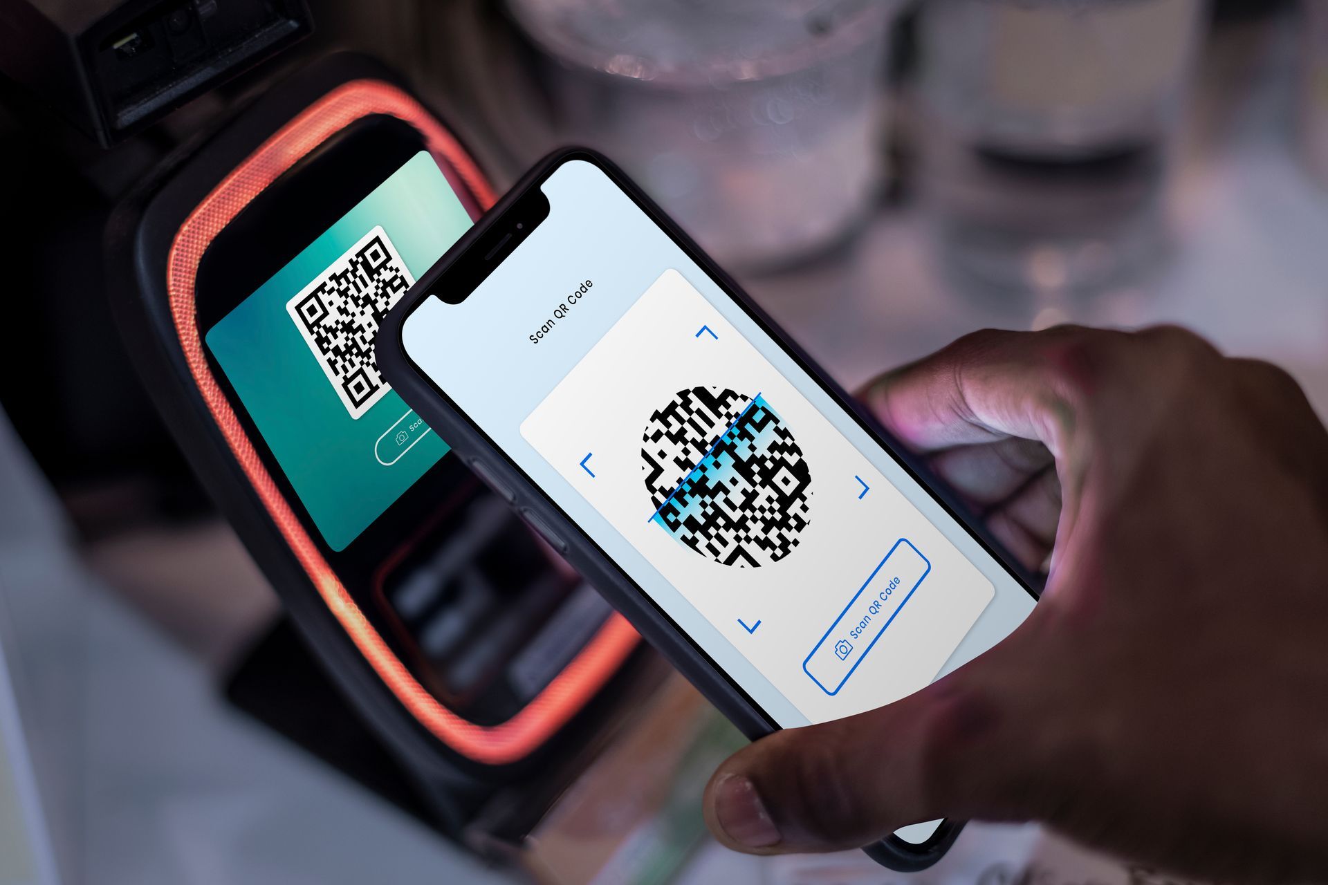 Hand holding a smartphone up to a QR code scanner for contactless check-in