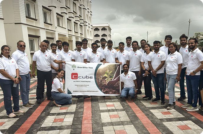Group of people in white shirts holding a banner outdoors in front of a building on a cloudy day