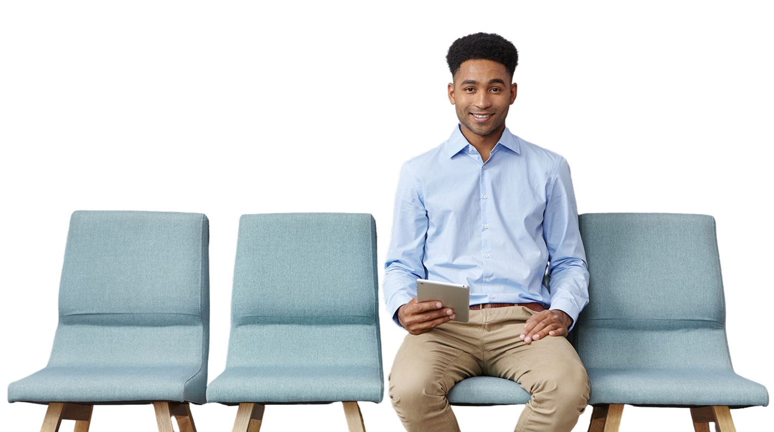 Man sitting on a row of blue chairs, holding a cup and smiling at the camera.