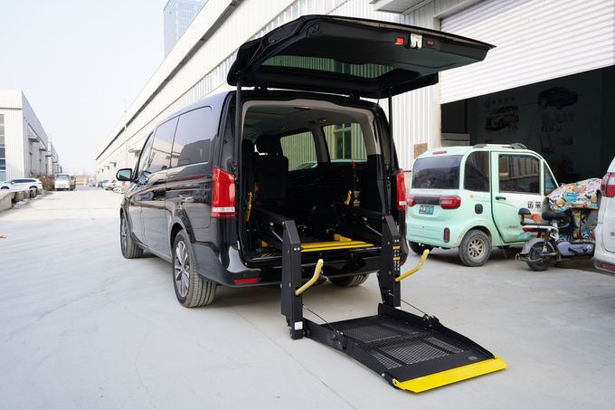 Black van with rear wheelchair lift deployed in a warehouse loading area