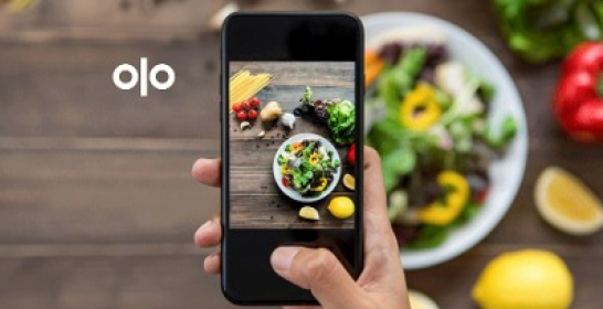 A person is taking a picture of a salad with a cell phone.