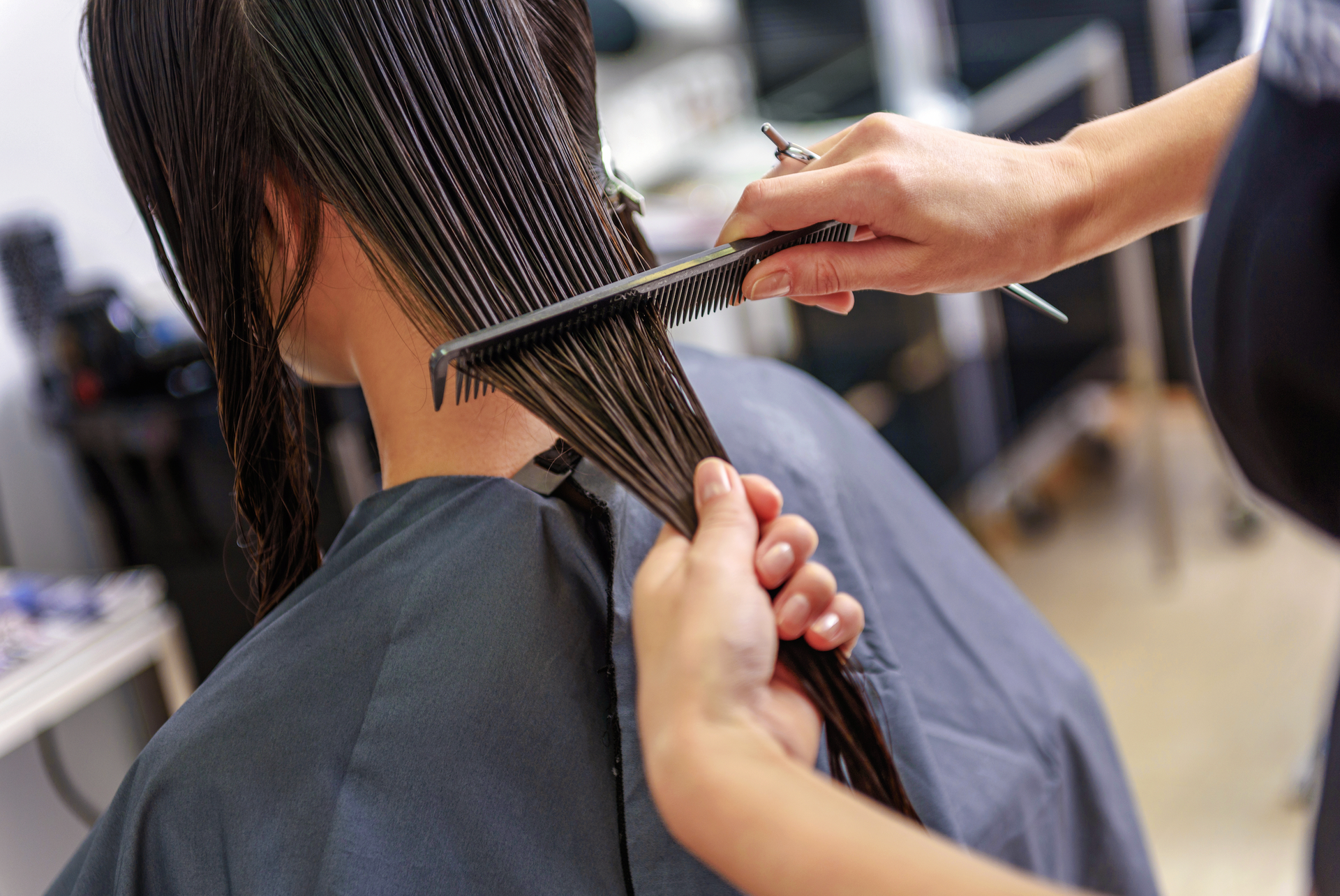 A woman is getting her hair cut by a hairdresser in a salon.