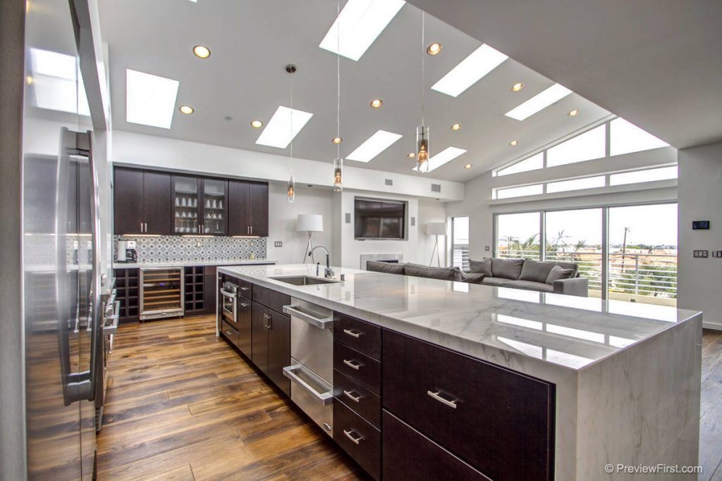 Modern bright kitchen with dark cabinets, large island, and stainless steel appliances