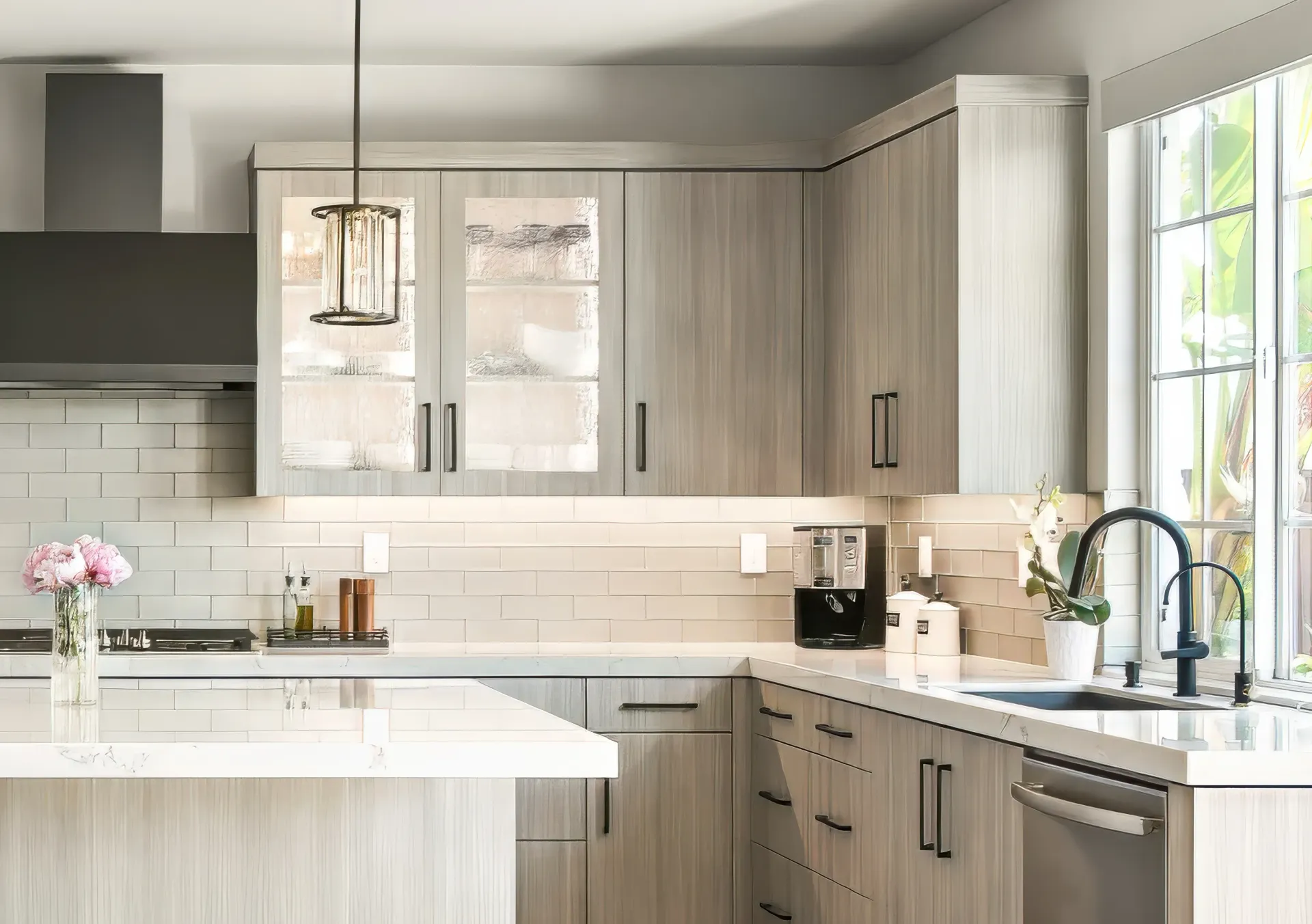 Bright modern kitchen with light wood cabinets, white countertops, and a window over the sink