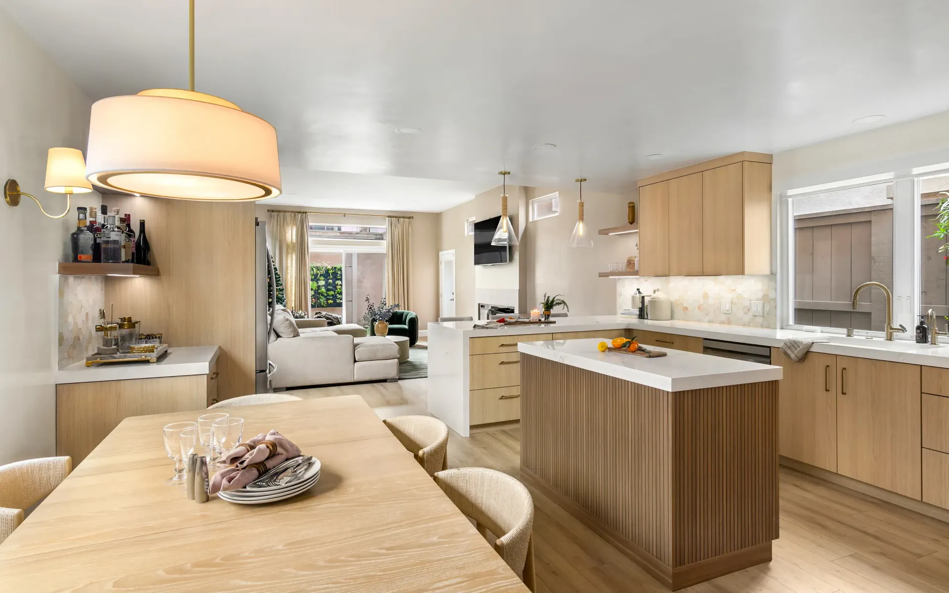 Bright modern kitchen with wood cabinets, island, dining table, and large windows
