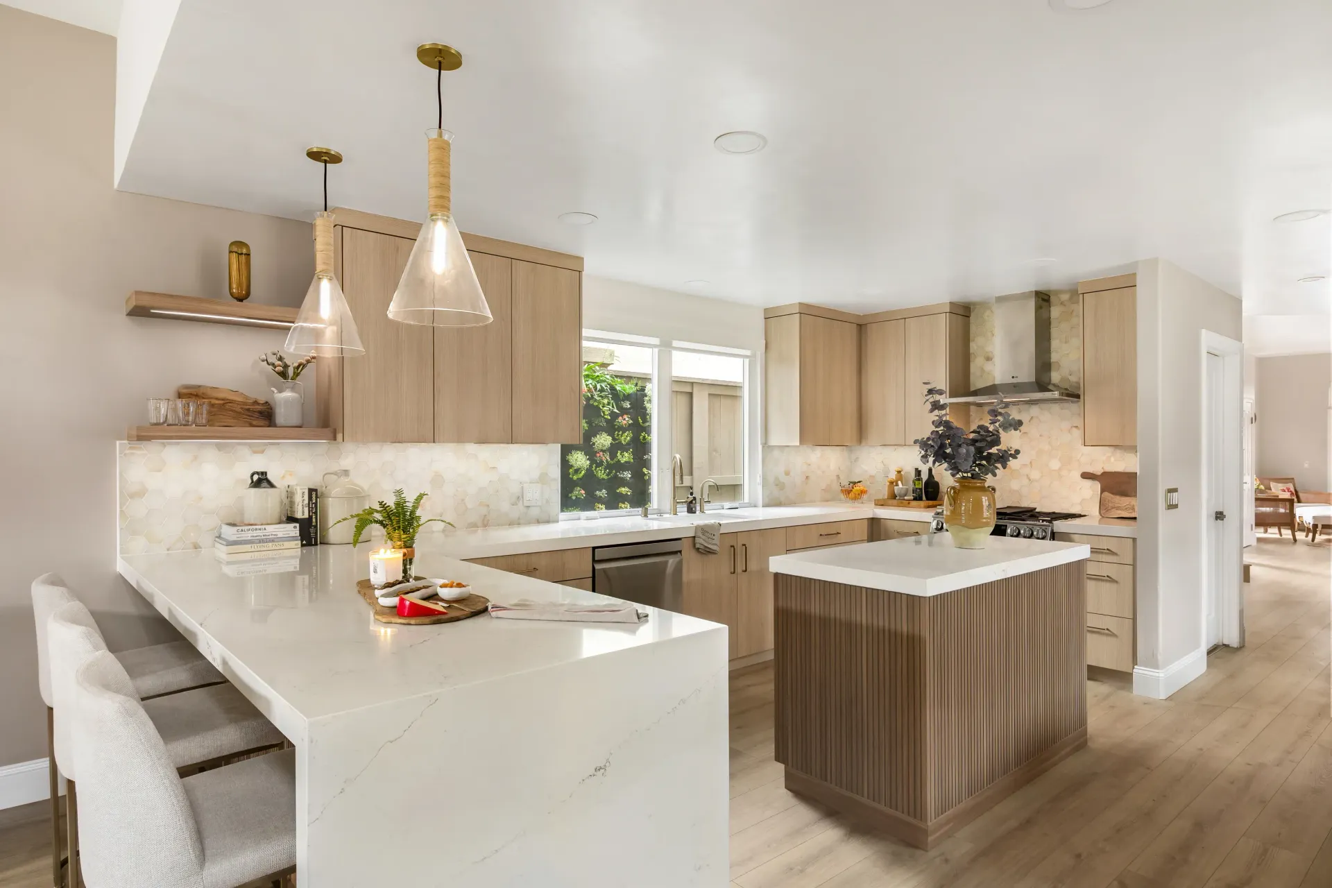 Modern kitchen with white countertops, wood cabinets, island, pendant lights, and a window over the sink