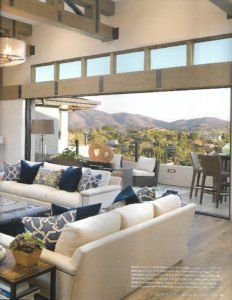 Modern living room with white sofas open to a patio and mountain view