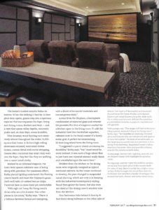 Modern living room with dark sofa, long table, patterned carpet, and wood-paneled accent wall.
