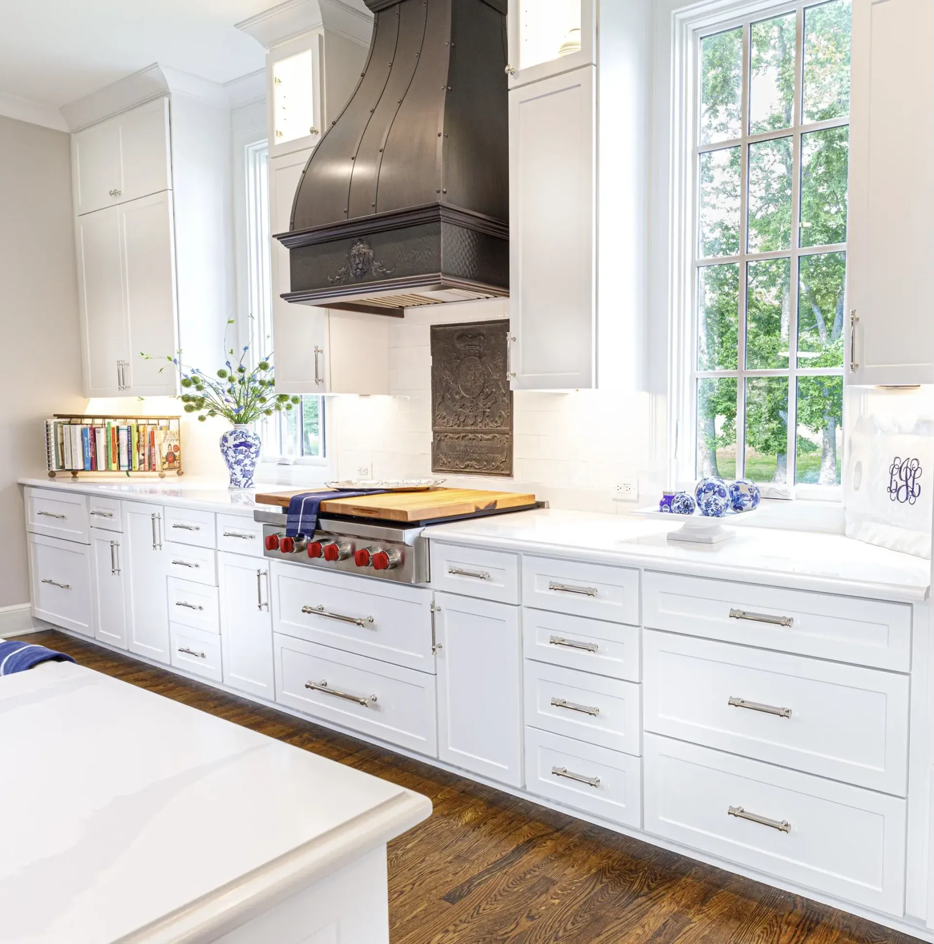 Bright white kitchen with large windows, white cabinetry, and a stainless steel range hood