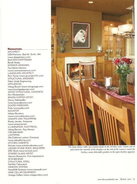 Warm dining room with wooden chairs, marble-top table, fireplace, and framed art on beige walls.