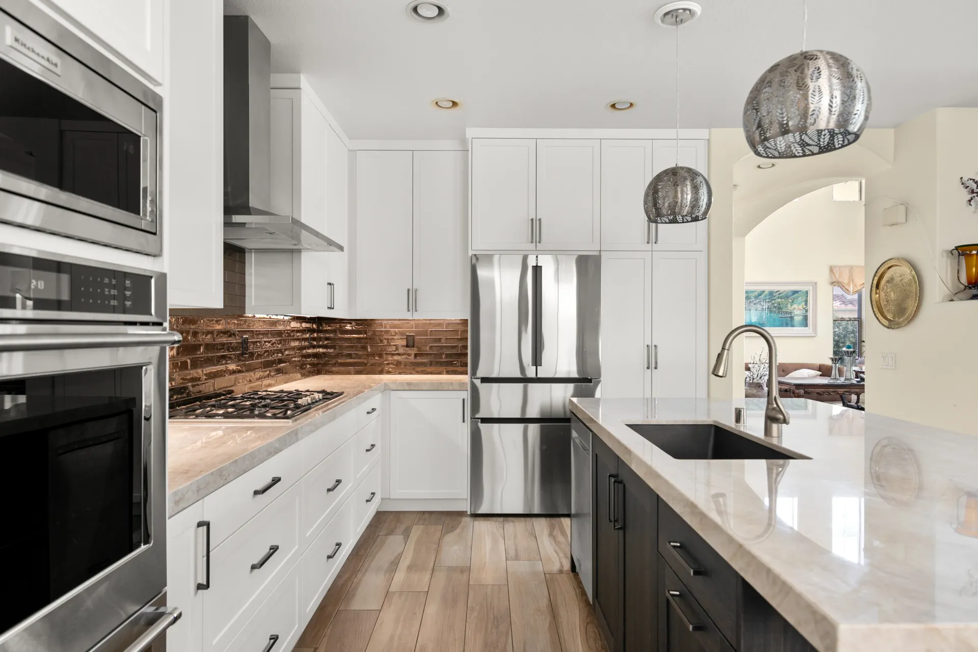 Bright modern kitchen with white cabinets, stainless appliances, marble island, and pendant lights