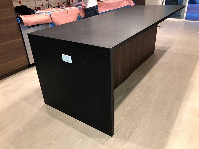 Black rectangular table with dark wood sides in a bright showroom.