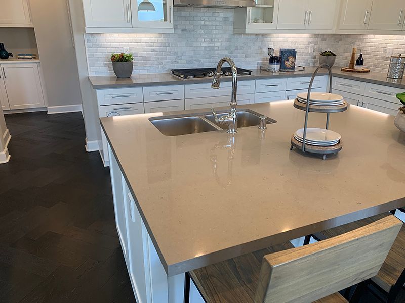 Modern kitchen with a large island, sink, beige countertop, and white cabinets