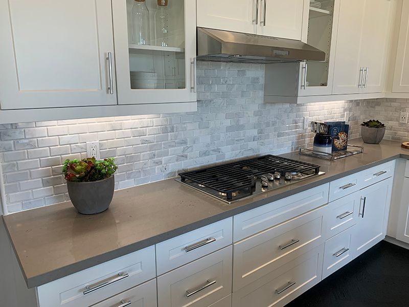 Modern kitchen with white cabinets, gray countertops, tile backsplash, and a gas cooktop