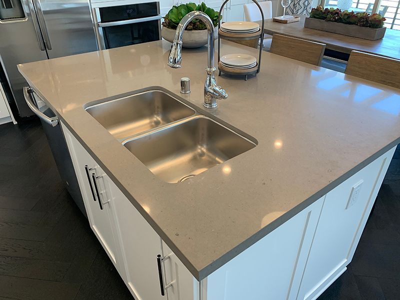 Kitchen island with double sink, chrome faucet, and beige countertop in a modern home.