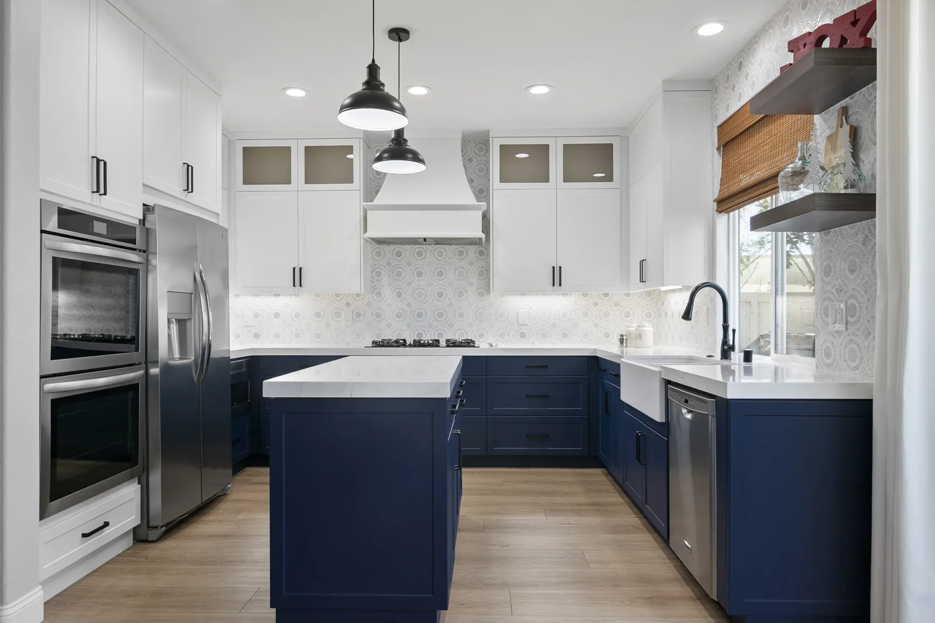 Modern kitchen with white cabinets, navy island, stainless appliances, and pendant lights