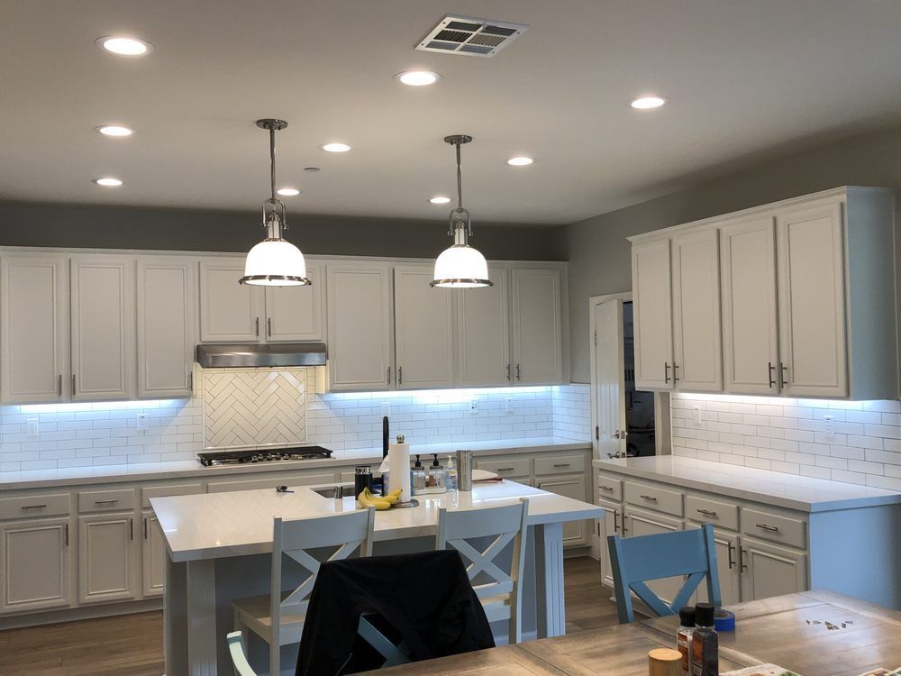 Modern white kitchen with island, pendant lights, and blue-tiled backsplash