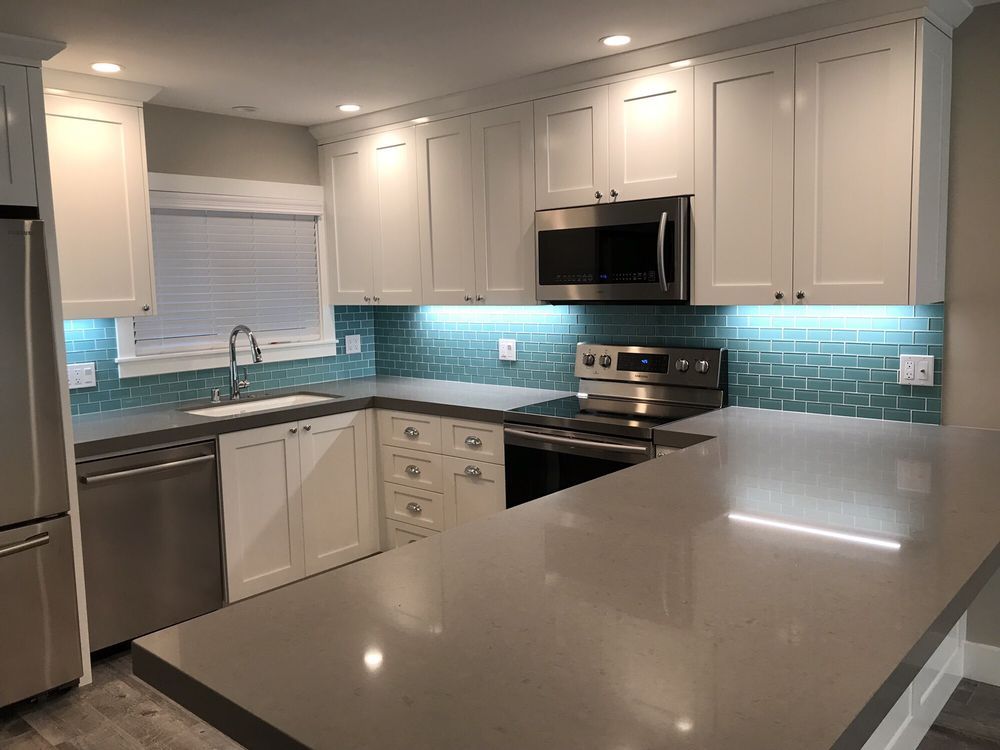 Bright white kitchen with teal backsplash, stainless appliances, and large island countertop