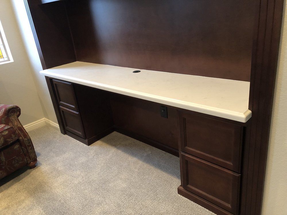 Built-in dark wood desk with white top against a wall in a carpeted room