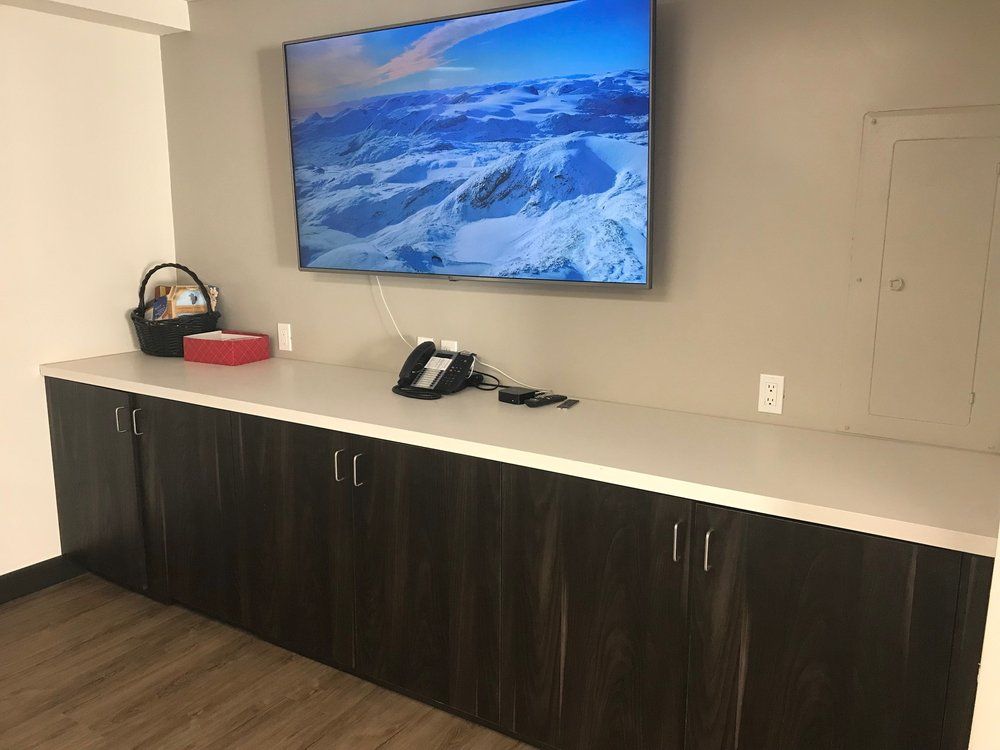 Break room counter with TV mounted above, dark cabinets below, and a phone on the countertop.