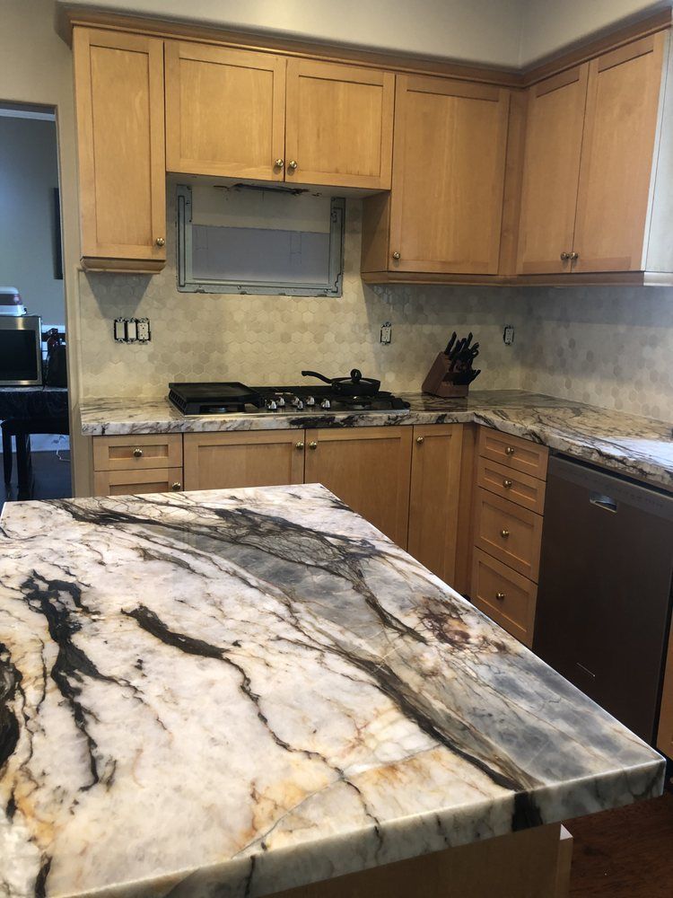 Kitchen with light wood cabinets, granite counters, and a marble-topped island in the foreground