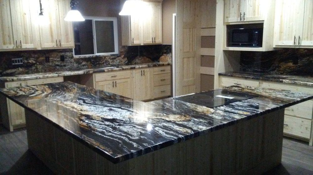 Modern kitchen with large black-and-white marble island and light wood cabinets