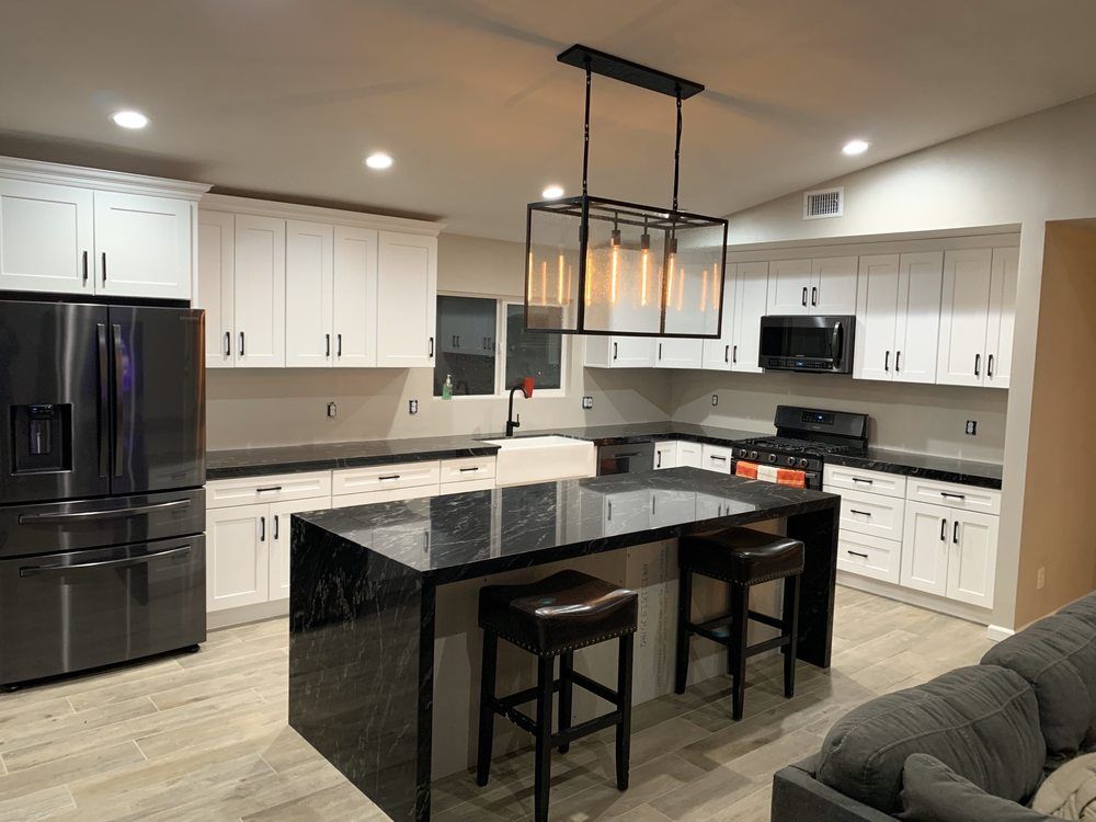 Modern kitchen with white cabinets, black appliances, island, and pendant light fixtures