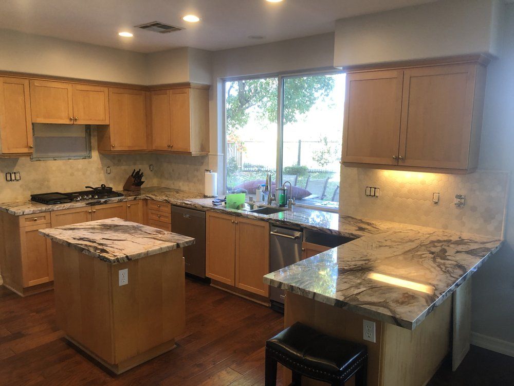 Kitchen with wood cabinets, granite counters, island, and a large window over the sink
