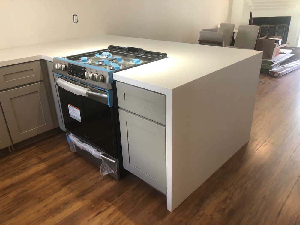 Modern kitchen with a large white island and a stainless steel range on the side.