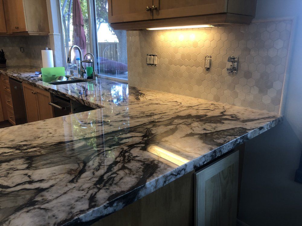 Kitchen countertop with polished marble-look stone and dark veining under under-cabinet lights