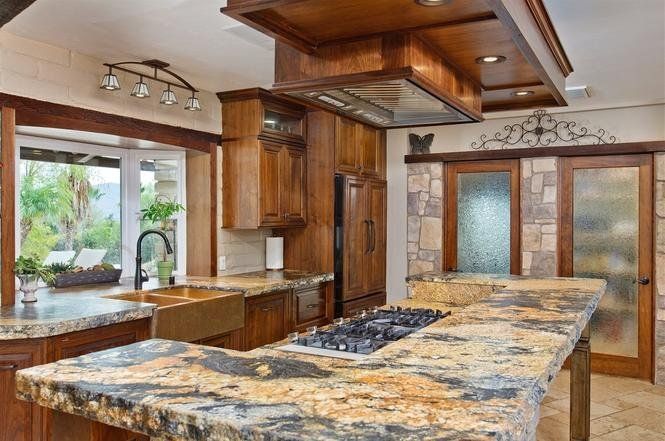 Spacious modern kitchen with granite island, wooden cabinets, and large windowed patio doors