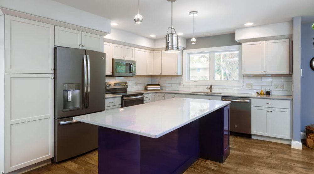 Bright modern kitchen with white cabinets, stainless steel appliances, and a purple island countertop.