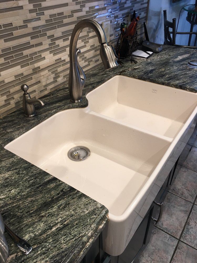 Double-basin white kitchen sink with chrome faucet and dark granite countertop