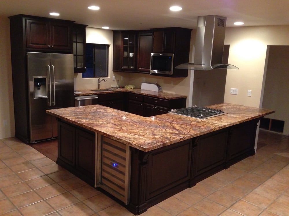 Modern kitchen with dark wood cabinets, stainless appliances, and a large granite island.