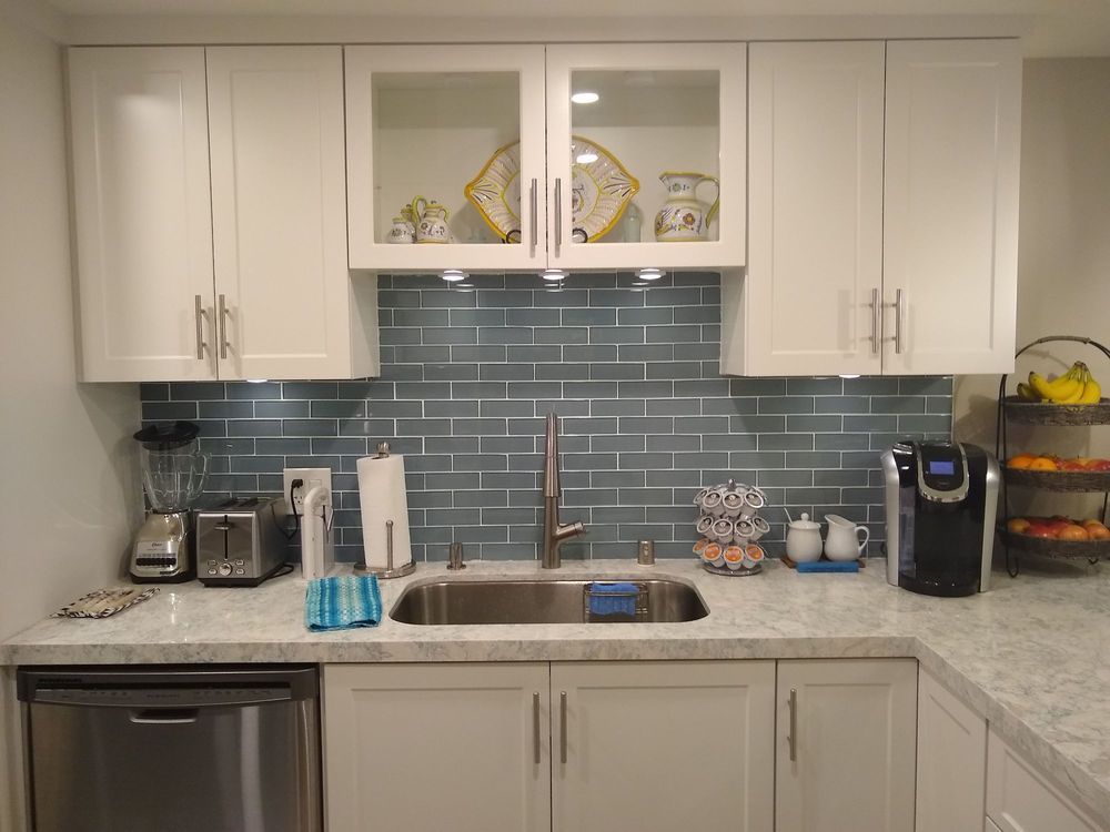 Modern kitchen with white cabinets, blue tile backsplash, granite counters, and stainless steel dishwasher