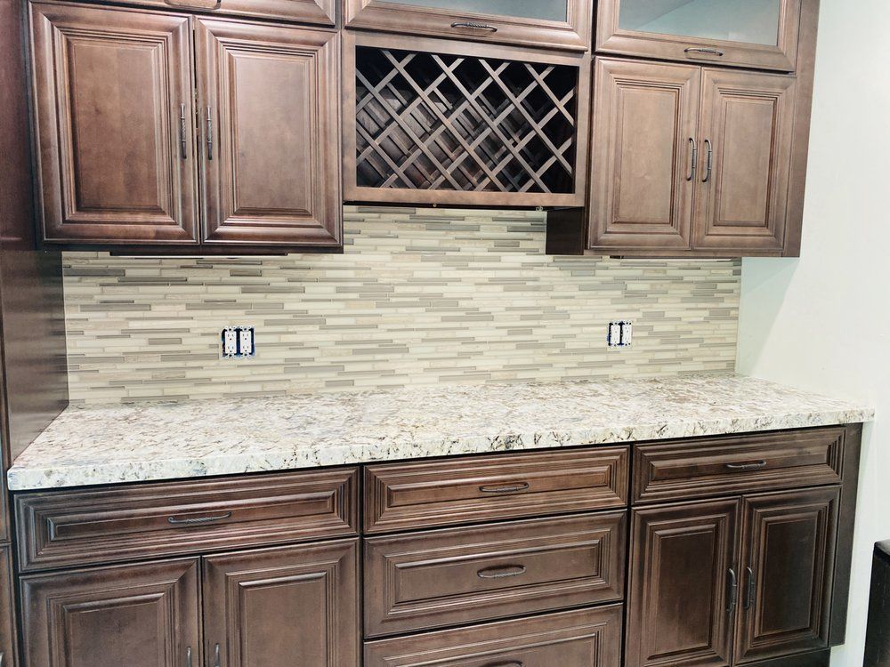 Built-in kitchen cabinets with granite countertop and tile backsplash, featuring a wine rack in the center