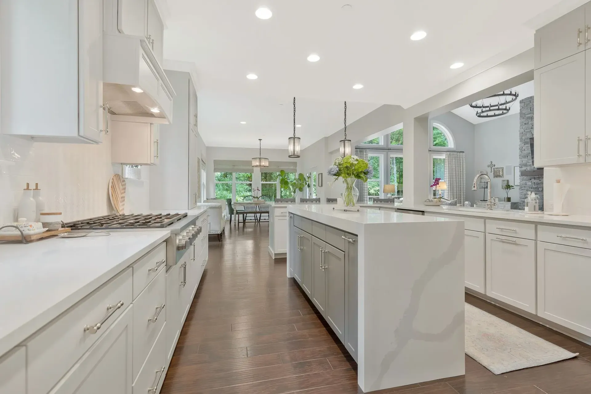 Bright white modern kitchen with a large island, stainless appliances, and pendant lights