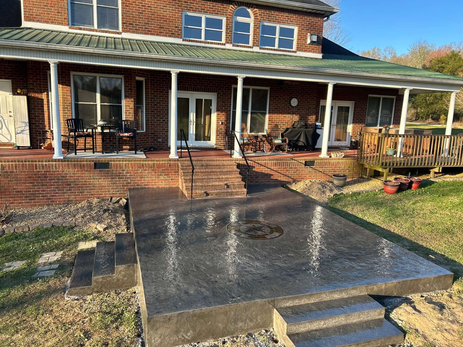 Brick house front porch with wet concrete patio and steps in the foreground