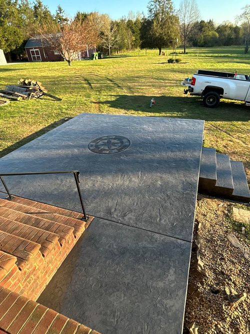 Concrete patio area in a grassy yard, with steps and a white pickup truck nearby.