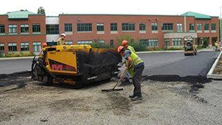 Les ouvriers du bâtiment travaillent sur une route devant un grand bâtiment
