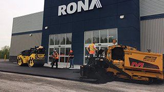 Un groupe de personnes travaille sur une route devant un magasin.