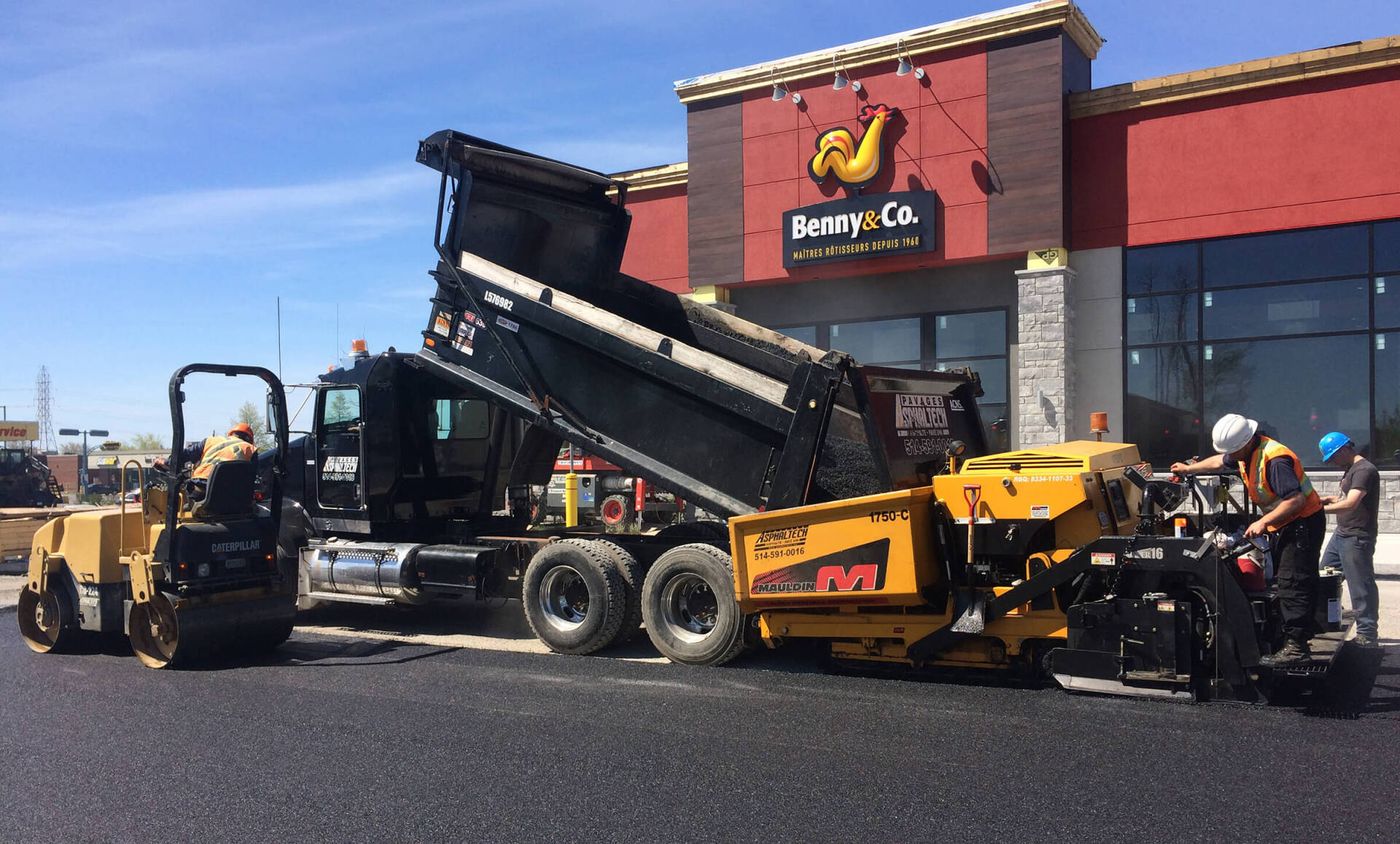 Un camion-benne est chargé d'asphalte devant un fast-food.