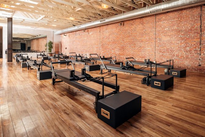 Interior of Pilates Cult studio in downtown Santa Barbara featuring reformers, exposed brick walls, and hardwood floors