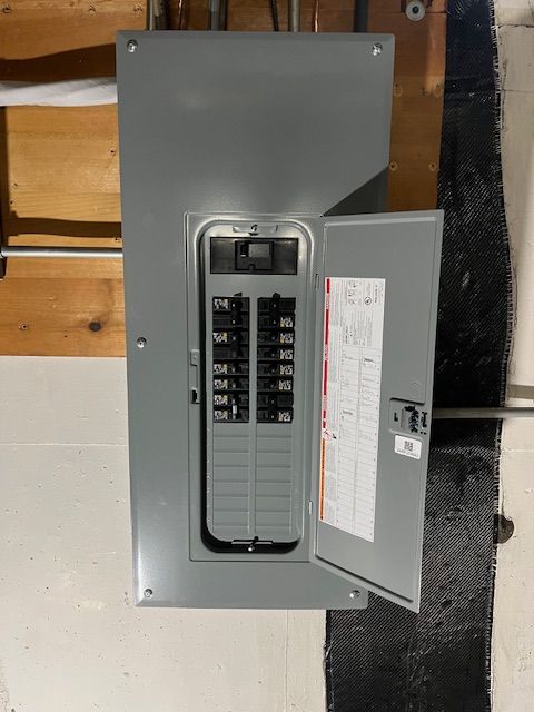A electrical box with the door open is hanging on a wall installed by Patriot Electrical Solutions.