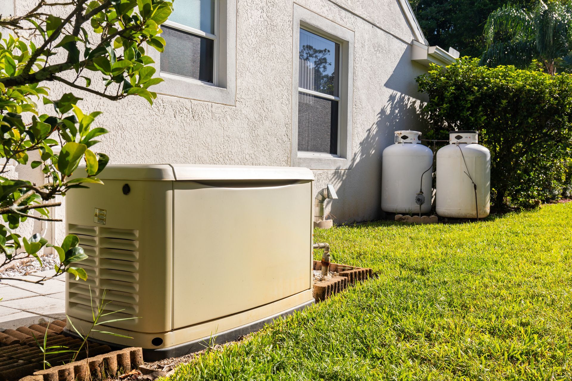 A generator is sitting in the backyard of a house next to two propane tanks installed by Patriot Electrical Solutions.