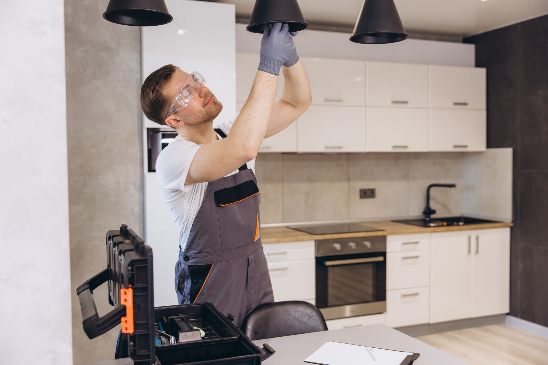 A man is fixing a light fixture in a kitchen. A man is fixing a light fixture in a kitchen.