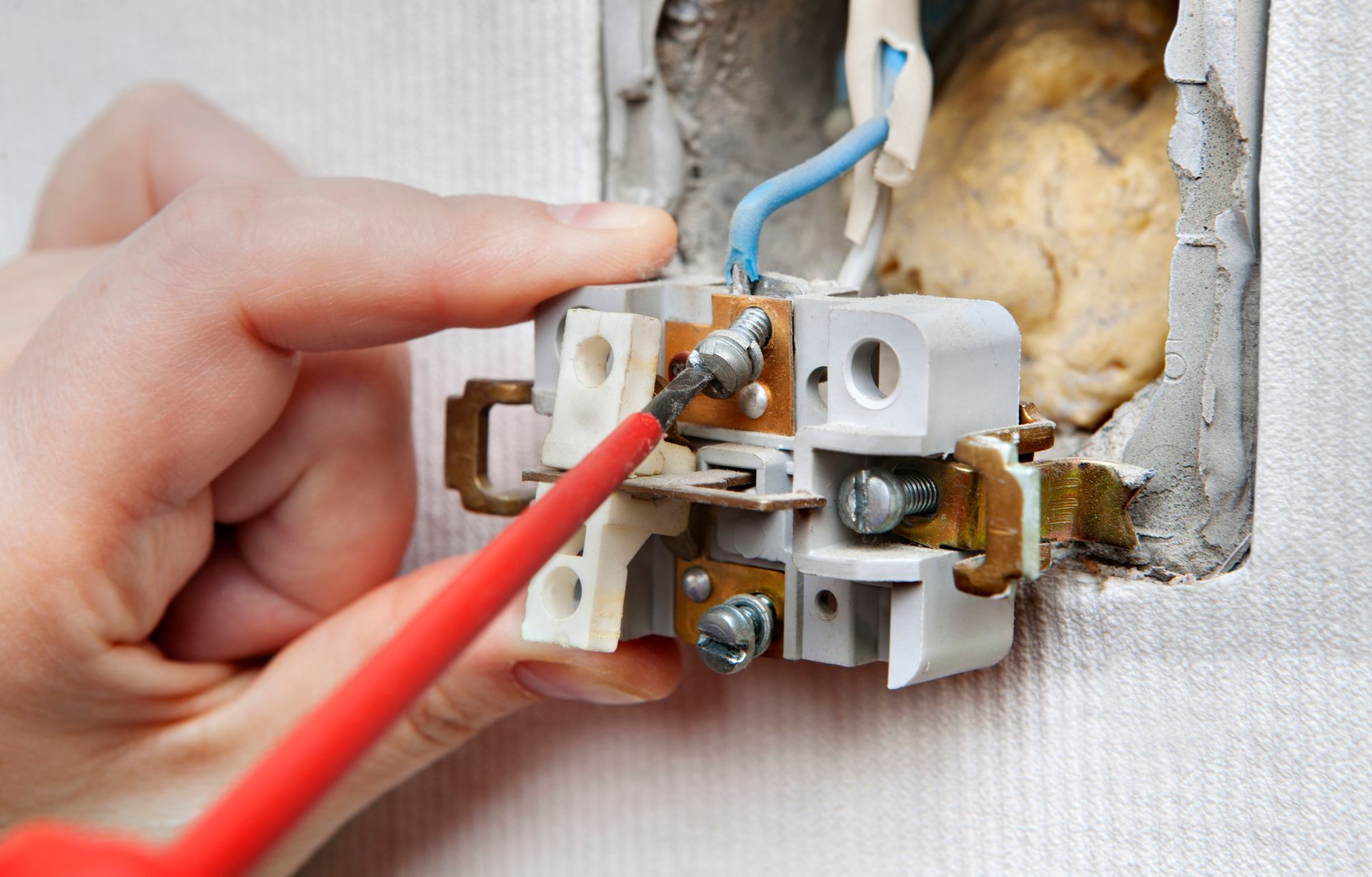 An expert repairing a faulty wall light switch as part of electrical repairs by Robert D. Samuels, I