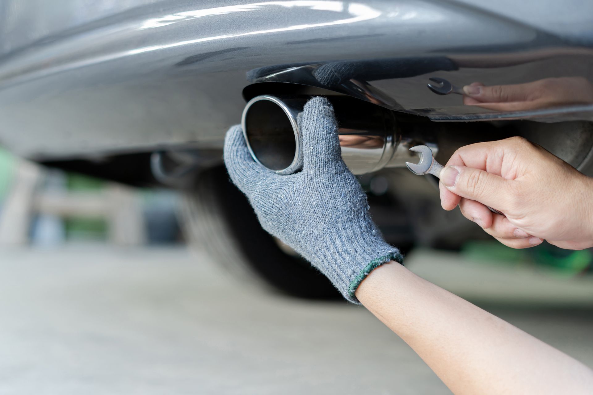 A man is working on an auto muffler. A man is working on an auto muffler.