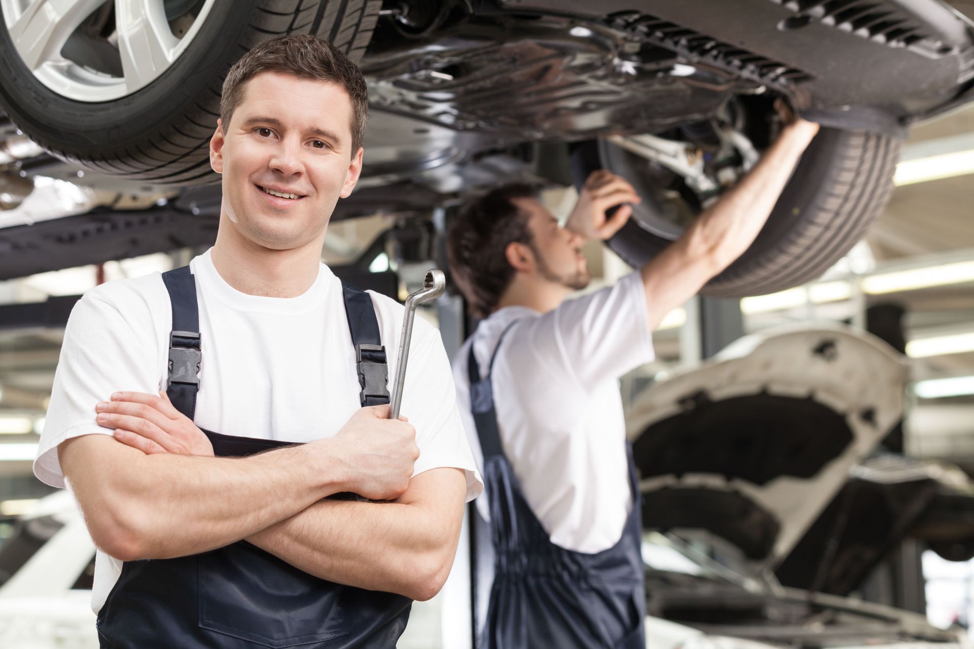 Two Mechanics Work Under a Car in a Garage - Northfield, NJ - Bargain Brakes
